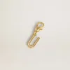 Ciondolo a forma di lettera U in ottone color oro con cristalli