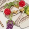 Lacci ricamati a righe color crema e grigio tortora con tre ciondoli a forma di frutto