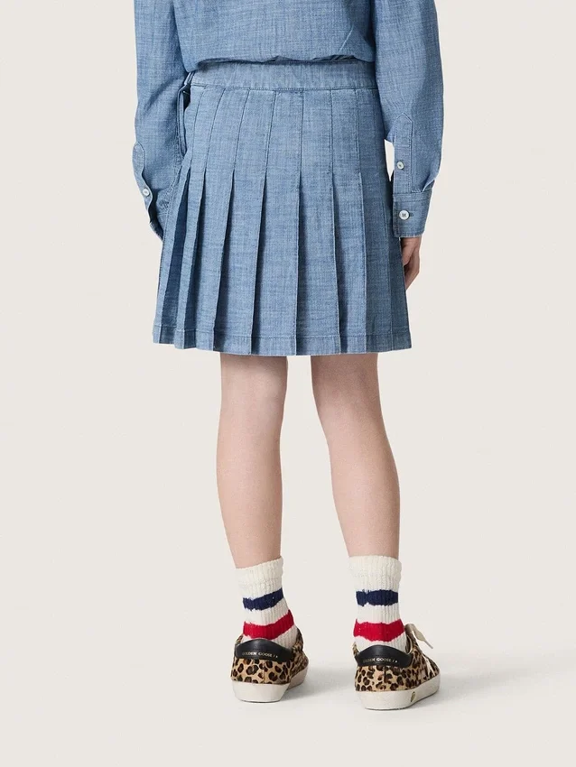 Minigonna a pieghe da bambina “Journey” in chambray di cotone azzurro con logo ricamato