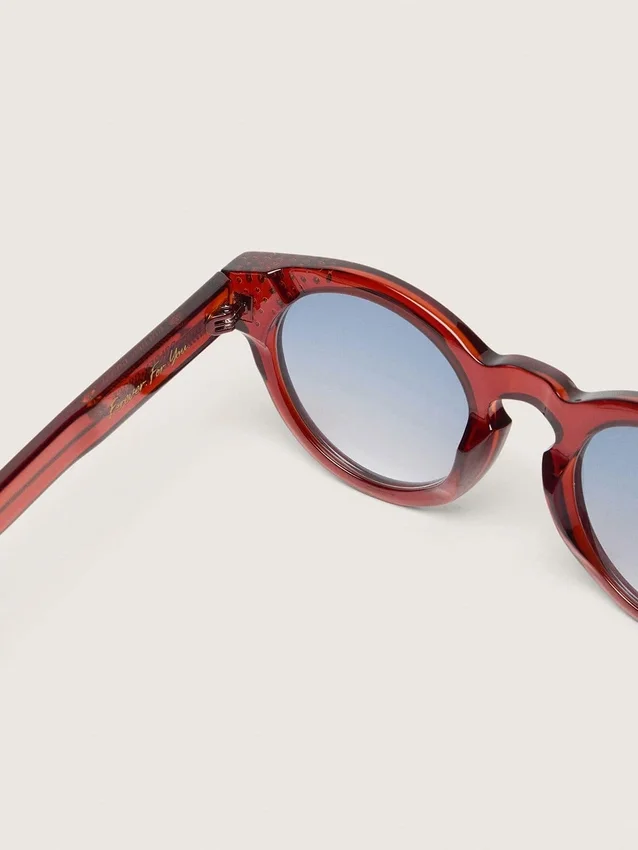 Occhiali da sole Cameron Panthos con montatura color miele, pietre preziose e lenti blu